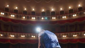 Actor on theater scene with his back to the camera. Man on stage bowing and actively gestures with his hands. Back view. video