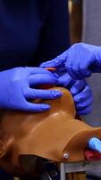 Training skills on dummy's head. Medical trainer demonstrates medical procedure to a student on a head. Practitioner learns on a doll. Close-up. Vertical video