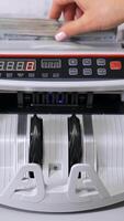 Counting operations in bank. Automatic mechanism counting hundred dollar banknotes. Electronic counting machine in bank. Vertical video