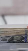 elektronisch Ausrüstung zum Zählen Papier Geld. Bank Arbeiter Putten ein bündeln von einer hundert Dollar Rechnungen in das Zählen Maschine zum Berechnung. Vertikale video