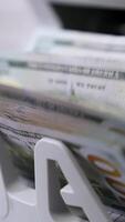Automatic calculation of paper money. Detailed view of Us dollar banknotes on currency counter machine. Business economy of usa. Macro shot. Vertical video