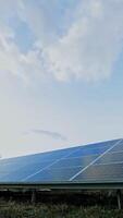 Sunny battery on the field. Blue photovoltaic panels in sunny reflection under the blue sky. Renewable source of energy. View from below. Vertical video