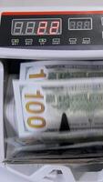 Automatic money counting in the machine. Electronic money machine is counting the dollar banknotes. Front view. Close-up. Vertical video
