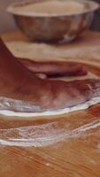 Baker kneading dough in flour on table. Hands of professional bakery chef on dough. Man forming dough of a round form for pizza. Vertical video