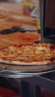 Pizza is ready. Pizzeria master making pizza. Chef pulling pizza out of the oven using the pizza spatula. Cook puts the finished pizza on the plate. Tasty pizza. Vertical video