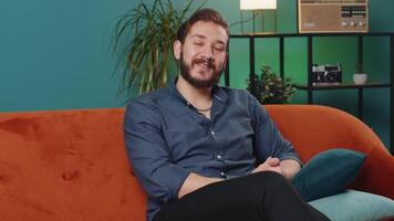 Lebanese man smiling friendly at camera, waving hands gesturing hello, hi, greeting at home on sofa video