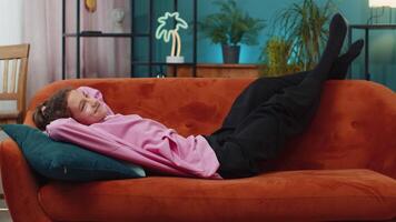Tired happy preteen school girl lying down on orange couch taking a rest, break, enjoy daytime nap video