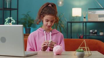 Preteen school girl putting one dollar cash money into piggy bank enjoying her first saving earning video