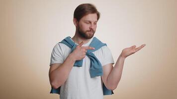 Caucasian man showing thumbs up, pointing at right on blank space, place for your advertisement logo video