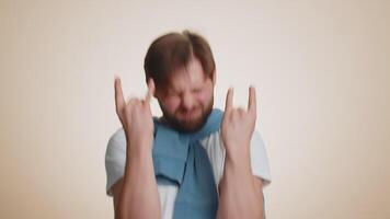Caucasian man showing rock n roll gesture by hands, cool sign, crazy expression, dancing celebrating video