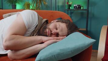 Tired young man lying down on comfortable couch, taking a rest, daytime nap relaxing falling asleep video