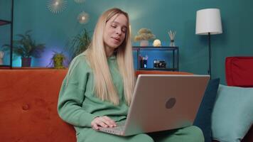 Woman sitting on home couch, looking at camera, making conference call with friends or family video