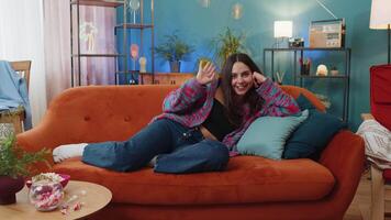 Caucasian woman smiling friendly at camera, waving hands gesturing hello hi greeting at home on sofa video