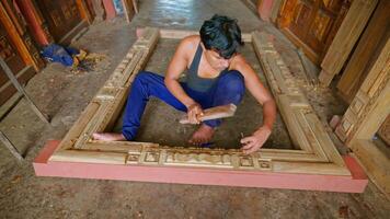 Artisan sits shaping timber board with mallet and chisel video