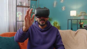 Man using virtual reality futuristic technology headset to play simulation 3D game at home video