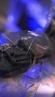 Robotic arm coated with plastic with lights on top moves working. Close up. Blurred dark backdrop with lights of garlands. Vertical video