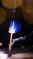 Highlighted spot where the robotic arms hold a writing pen. Demonstration of high precise work of Da Vinci equipment. Lights at dark blurred backdrop. Vertical video