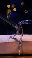 Small forceps of robotic arms tie a rope on the scroll. High precise equipment performs delicate work making a knot. Close up. Dark backdrop with blurred lights. Vertical video