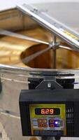 Metal electronic centrifuge device rotating the wooden frames with honeycombs. Extraction of organic honey at apiary. Vertical video