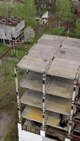 Ruined industrial building. Old unfinished architecture of a factory. Abandoned territory of manufacturing. Aerial view. Vertical video