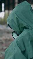 Human in radioactive territory. Person in a hazmat suit and gas mask walking in empty ruined building. Abandoned place after chemical attack. Rear view. Vertical video