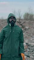 Man in safety suit and respirator on garbage background. Mad man in protective costume and gas mask dancing in abandoned place in radioactive zone. Vertical video