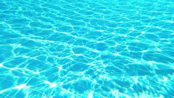 Surface of the bottom of a blue pool with glare from the sun and waves video