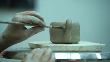 A student cleans a clay cup with brushes on a rotating table video