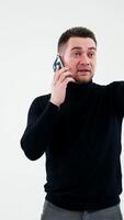 Smiling man with a phone isolated on white background. Handsome businessman talking on the mobile phone and gesticulating. E-business concept. Vertical video