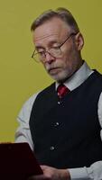 Thoughtful old businessman with a folder. Mature man becomes happy after finding the right solution to his project. Positive emotions. Vertical video