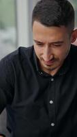 Man with concerned expression on his face looking at laptop. Busy man thinking over his problems at work, hard tasks or challenges. Vertical video