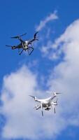 Drones hovering across the sky. Two drone quad copters with high resolution digital camera flying Vertical video