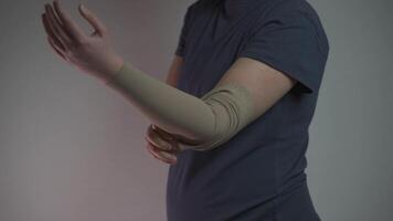 Prophylactics of thrombosis. Woman removes compression sleeve from left hand on gray background. Effective anti-thrombosis therapy involves compression sleeves to improve vein health and blood flow. video