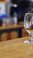 Transparent glass with ice cubes. Bartender is putting crystal ice cubes in a glass before preparing an alcoholic cocktail to customers on the bar table. Vertical video