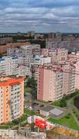 New architecture in the city. Luxury design of apartment building in a sunny day. Orange and white high-rise apartment with balconies. View from the drone Vertical video