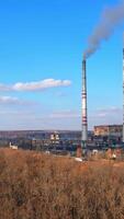 High voltage post. High-voltage tower sky background, factory pipe with smoke over it. Earth pollution and industrialization concept. Selective focus Vertical video