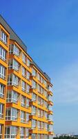 Beautiful design of multistory building. New apartment with balconies against blue sky. Exterior of residential building. Camera rising up. Slow motion video