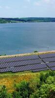Solar cell panels field. Motion camera view of the rows of long sunny batteries on green field. Renewable alternative energy concept. Future technology concept Vertical video