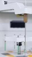 Machine detail is moving lowering and going up. Advanced equipment performing science medical analysis and testing. Close up. Blurred backdrop. Vertical video