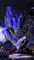 Futuristic Da Vinci robot using old writing appliances. Robotic arms coated in plastic write on the paper on operational table. Christmas decorations at backdrop in dark room. Vertical video
