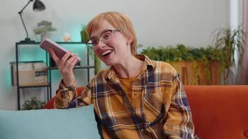 Happy excited young woman making phone call conversation loudspeaker talking with friend at home video
