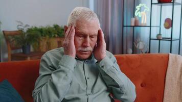 Displeased grandfather man rubbing temples to cure headache problem, suffering from migraine, stress video