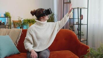 Woman using virtual reality futuristic technology headset to play simulation 3D game at home video