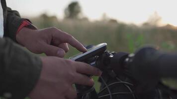 Cyclist use bicycle computer on handlebars of mountain bike in nature. Traveler on cycle looks at map, builds route using GPS on bicycle navigator. Activity tracker and offline maps for bike rides. video