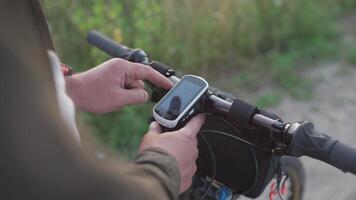Cyclist use bicycle computer on handlebars of mountain bike in nature. Traveler on cycle looks at map, builds route using GPS on bicycle navigator. Activity tracker and offline maps for bike rides. video