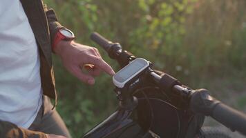 Cyclist use bicycle computer on handlebars of mountain bike in nature. Traveler on cycle looks at map, builds route using GPS on bicycle navigator. Activity tracker and offline maps for bike rides. video