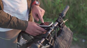 Cyclist use bicycle computer on handlebars of mountain bike in nature. Traveler on cycle looks at map, builds route using GPS on bicycle navigator. Activity tracker and offline maps for bike rides. video
