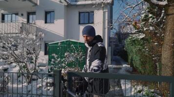 Male bicyclist leaves courtyard of house with bicycle in sunny winter weather with snow. Commuter leaves house by opening the wicket in Europe in winter. Daily use of the bicycle in all weathers. video