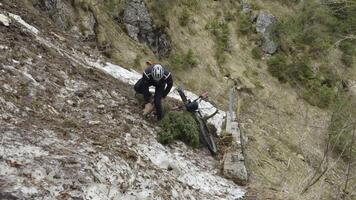 Man cyclist pulls bicycle through avalanche in mountains. Bicyclist is trapped in obstacle and is pulling his cycle through an ice slide with bicycle in his hands. Avalanche on cycling route in Alps. video