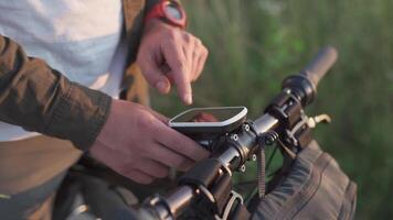 People, sports, active lifestyle concept. Cyclist using navigator device examines map and looks for GPS coordinates on screen of gadget while cycling outdoors. Activity tracker on handlebars of cycle. video